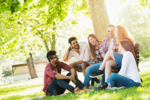 A group of diverse friends sitting in a park laughing on a sunny day.