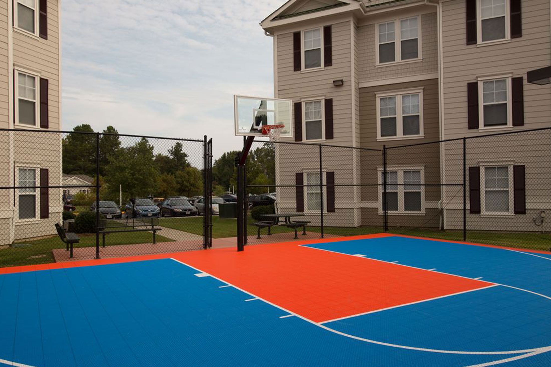 Gated basketball court with single net and benches.